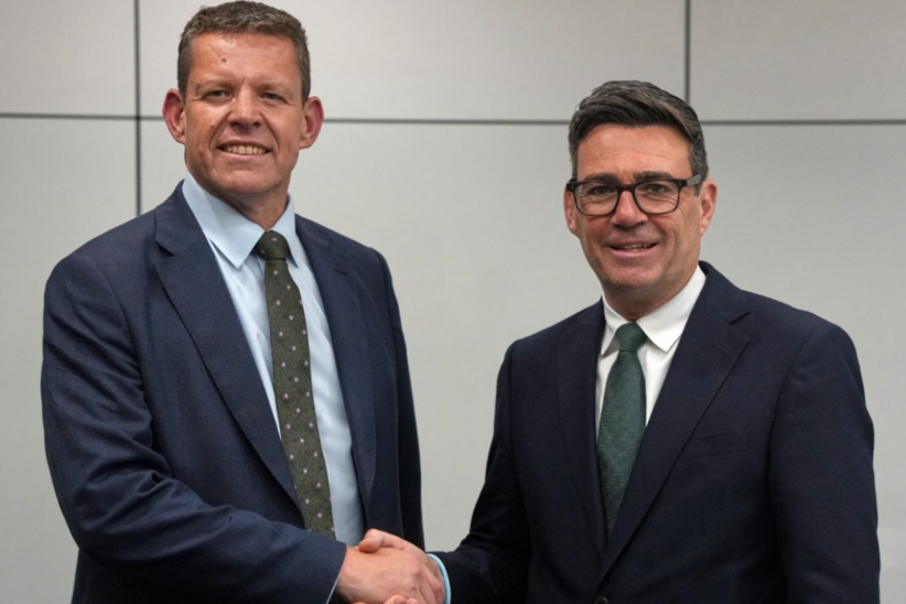 Rhun ap Iorwerth shaking hands with Andy Burnham in front of a grey backdrop.