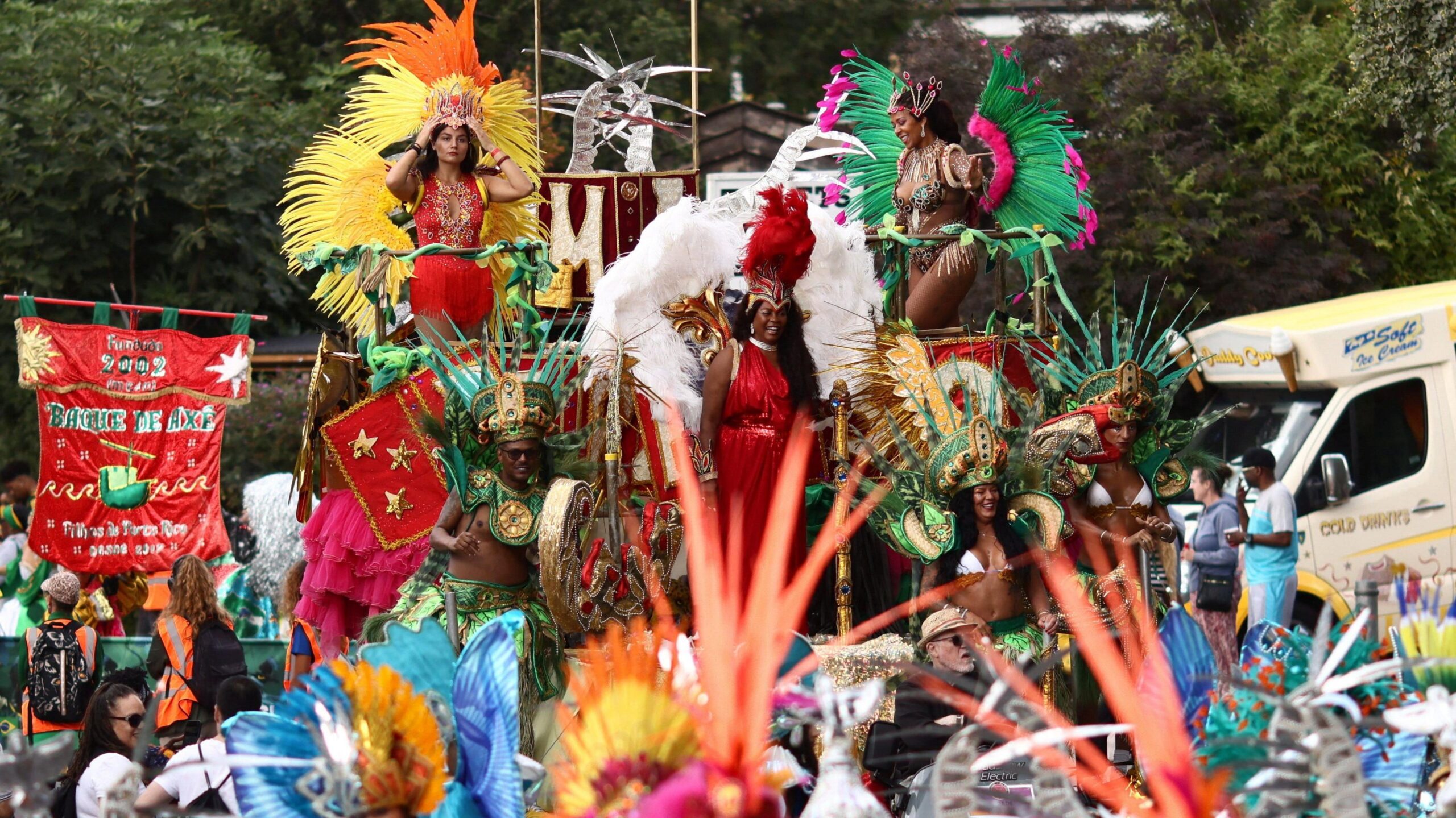 People in bright feathered costumes stand on a parade float.