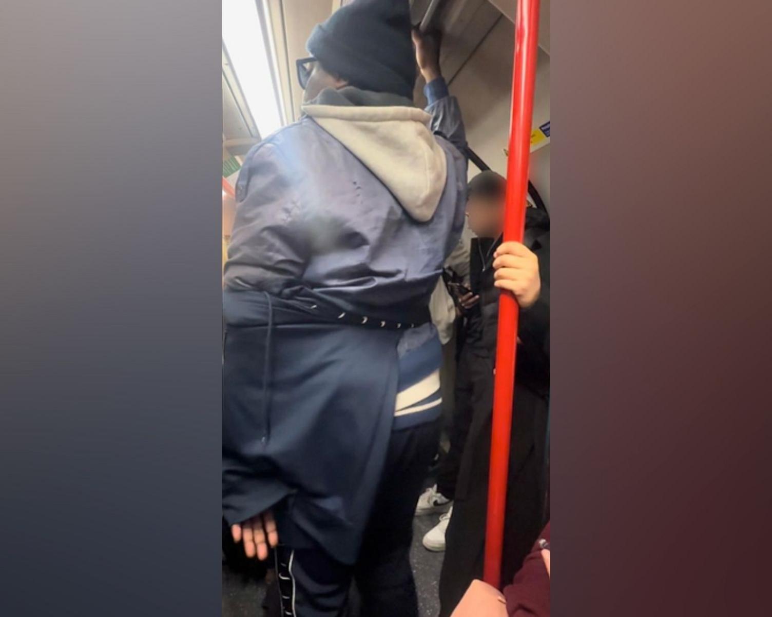 A photo taken on a busy tube, which captures Levy using his clothing to conceal his hand