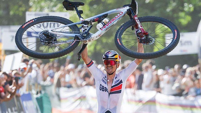 Tom Pidcock lifts his bike in celebration