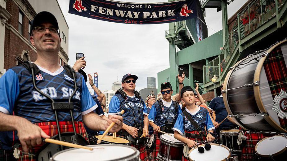 A pipe band outside Fenway Park wearing tartan tops bearing the words "Rex Sox"