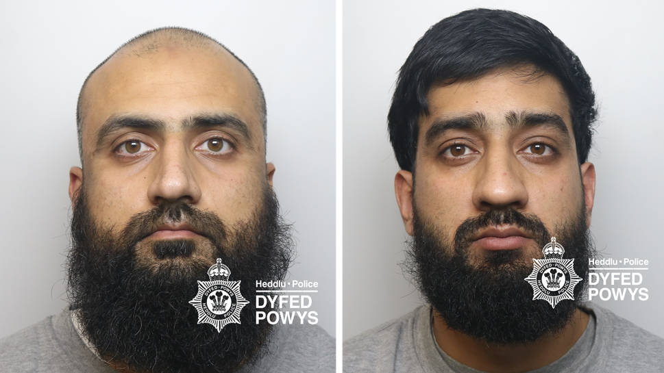 A composite image of two men's mugshots. One on the left is bald with a black beard. The one of the right has a black bears and short black hair. They both look at the camera expressionless. There is a Dyfed-Powys Police watermark on it.
