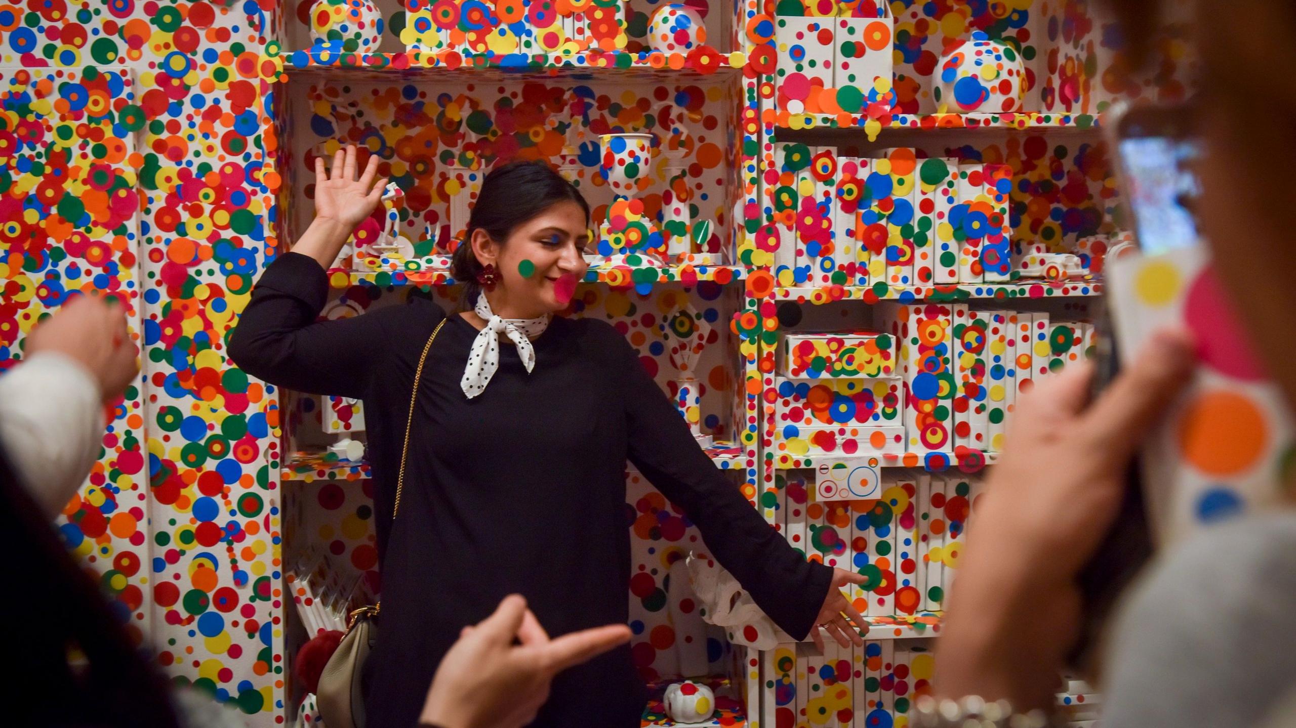 A gallery visitor poses in front of a wall covered in multi-coloured spots on the final day of the Yayoi Kusama: Infinity Mirrors exhibit at the Smithsonian Institute's Hirshhorn Museum on Sunday, May 14, 2017