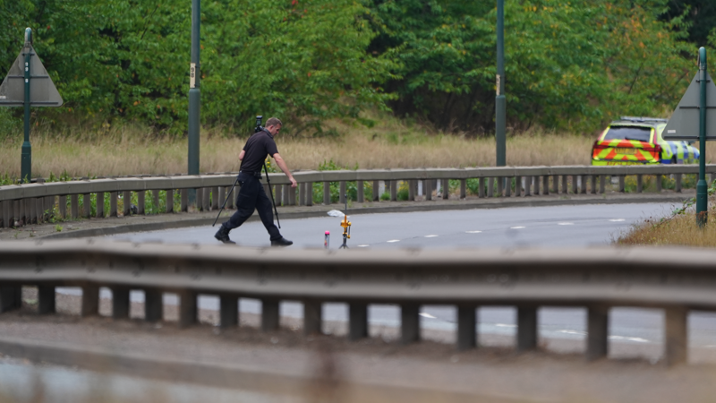 A police officer in a black uniform is walking across the A66, which is completely closed to traffic.