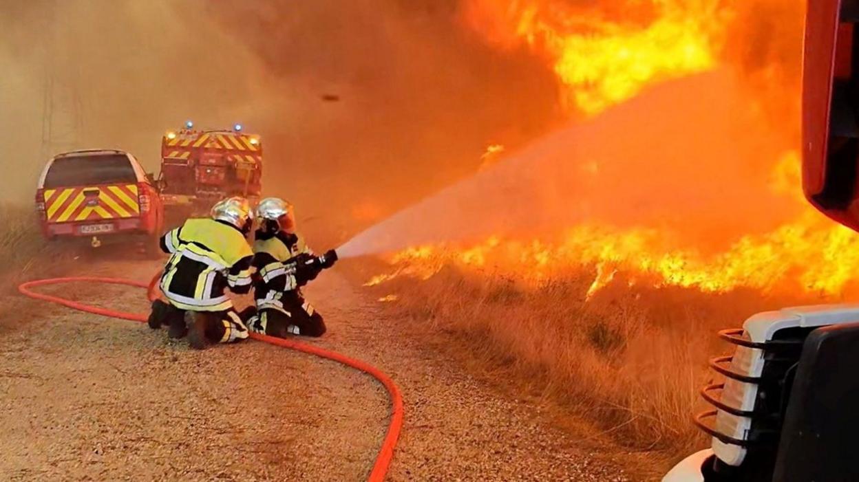 Firefighters work as flames and smoke rise during a wildfire, amid drought conditions following a heatwave and water shortages across much of France, in Saint-Jean-d'Illac, Nouvelle-Aquitaine, France, July 27, 2026, in this screengrab taken from a video.