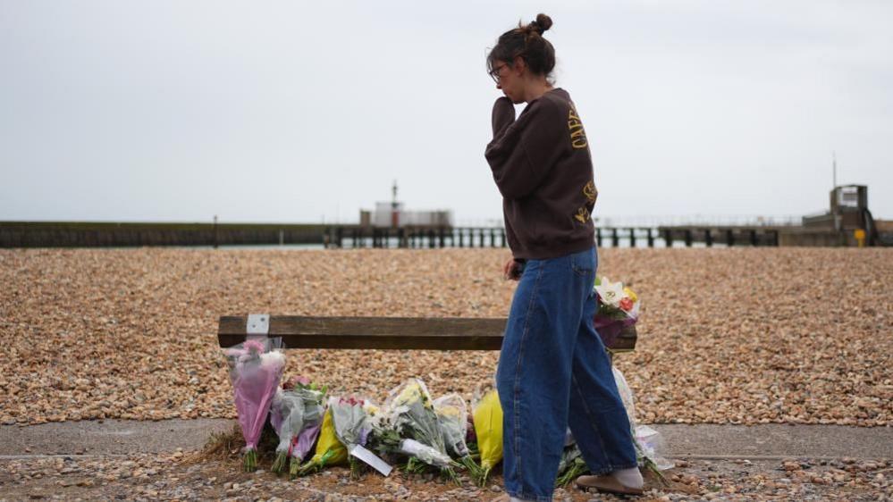 A woman stood next to floral tributes in Shoreham