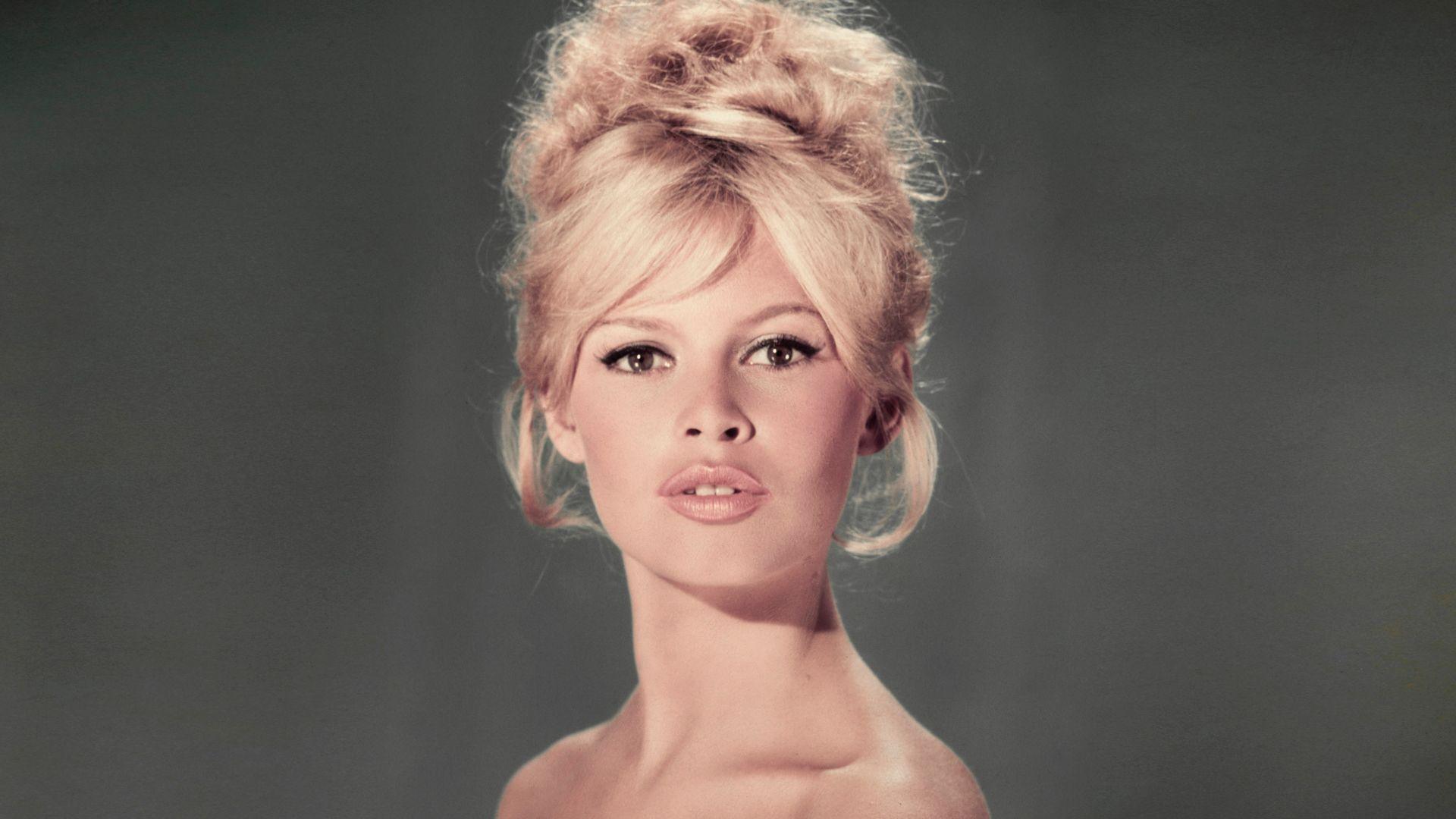 Studio portrait of actor and model Brigitte Bardot wearing a light blue off-the-shoulder dress