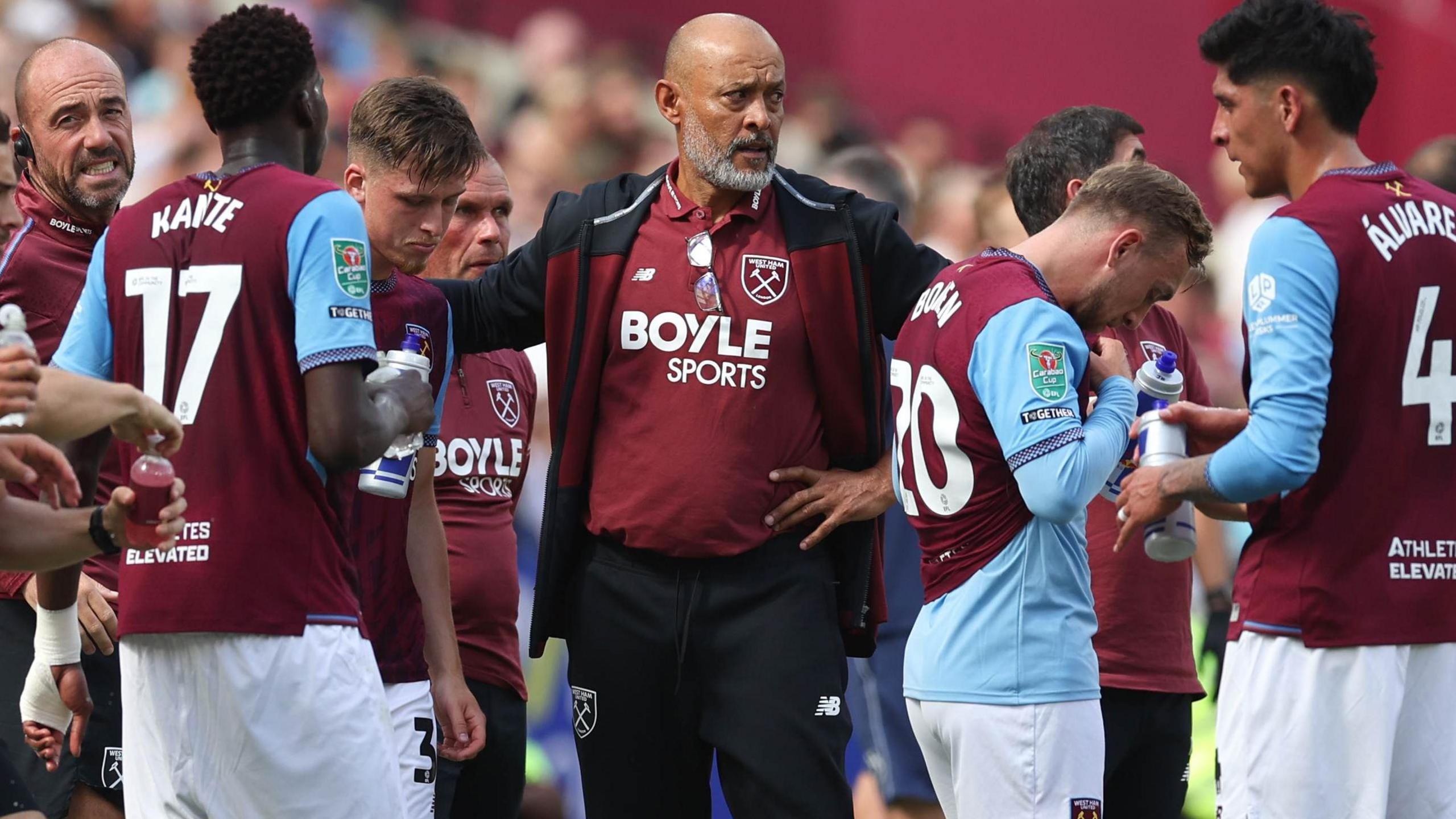 Nuno Espirito Santo, wearing a claret West Ham polo shirt under a navy blue and claret hooded jacket, speaks to his players during a hydration break in the EFL Cup game against Portsmouth.