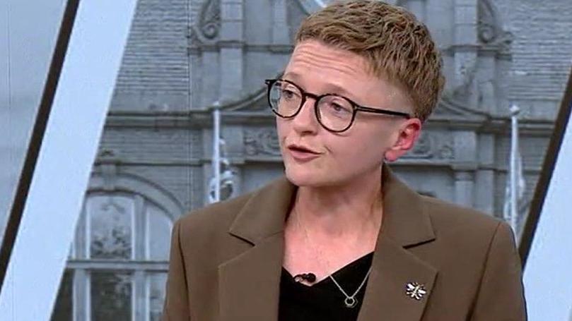 Bev Craig, who is wearing glasses and a brown jacket over a black top, is talking during a mayoral by-election debate.