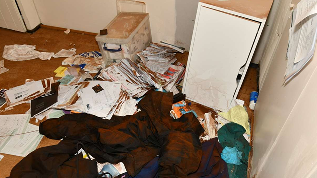 A room at a funeral parlour with hundreds of pieces of documents strewn across the floor among pieces of fabric.