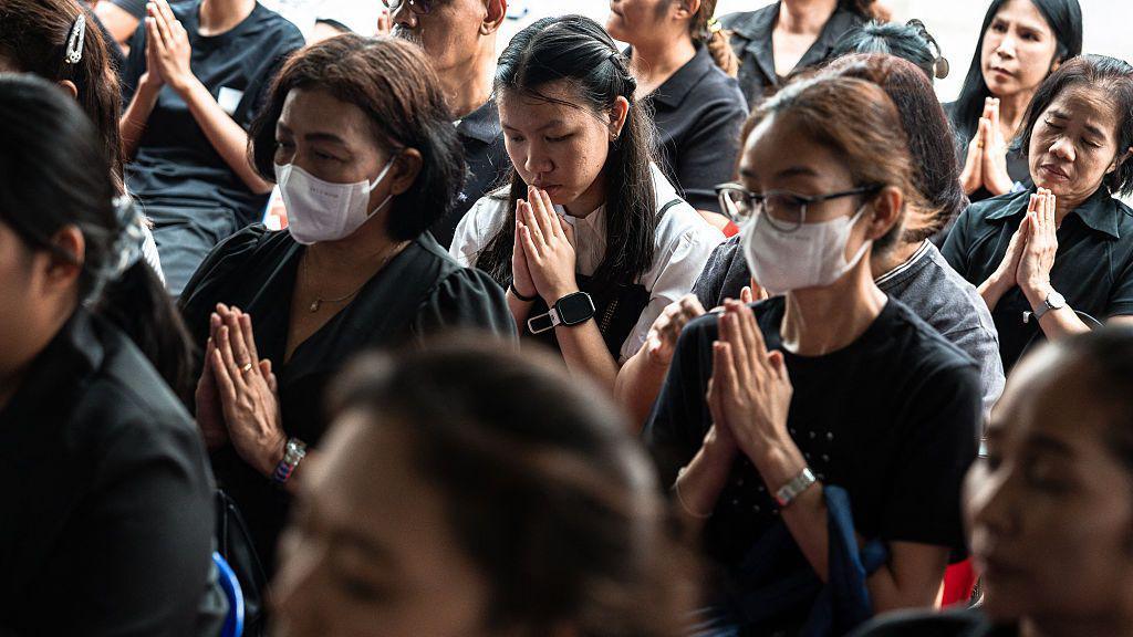 Women praying, some wearing face masks
