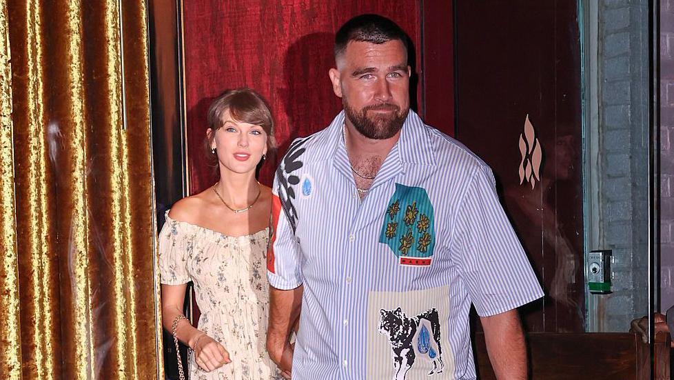 Taylor Swift and Travis Kelce were seen walking out of a restaurant on their wedding weekend in New York City. She is wearing a floral dress and he is seen in a short-sleeved button-down shirt and pants.