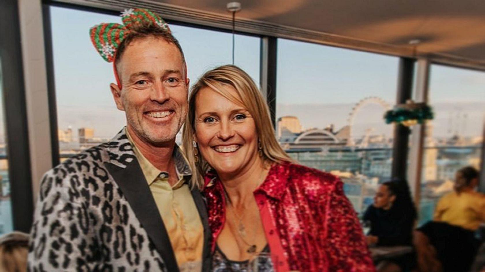 A middle-aged couple are in fancy dress at a party. They look happy.