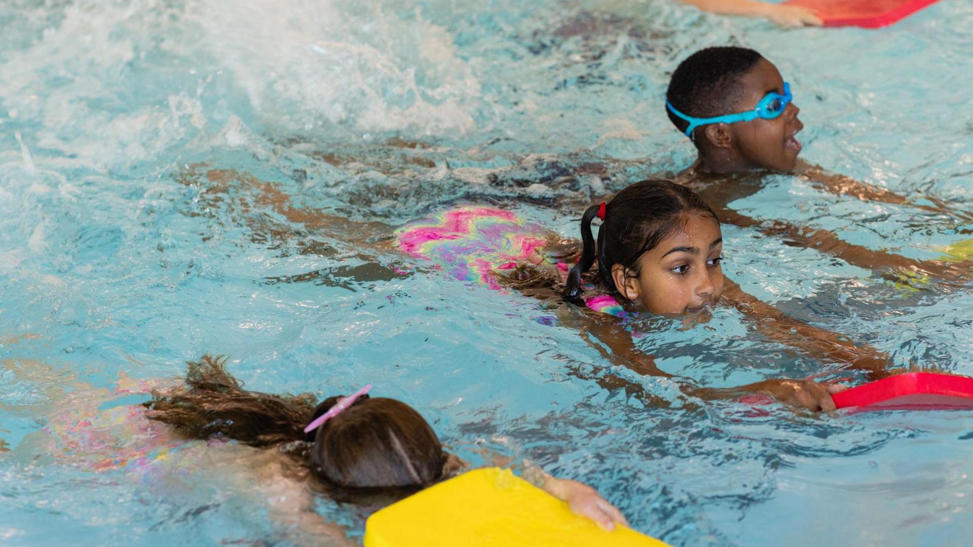 A group of children swimming using swimming floats in a swimming pool