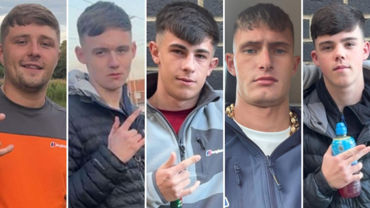 Five young men in their late teens and early 20s. They all have similar haircuts, with a fringe and faded back and sides. Four of them are gesturing with their fingers. Three of them extend their thumb, index, and pinky fingers - leaving their middle and ring finger tucked down. One points with his index and middle finger whilst holding a Lucozade bottle. They are all dressed in casual clothing.