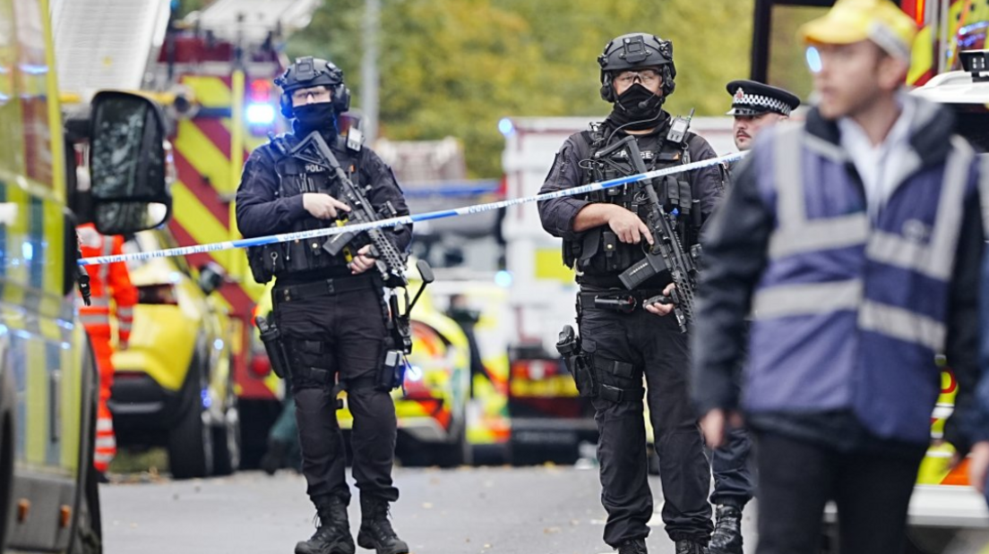 Armed police at the scene at the attack at the synagogue in Manchester, with police vehicles in the background.