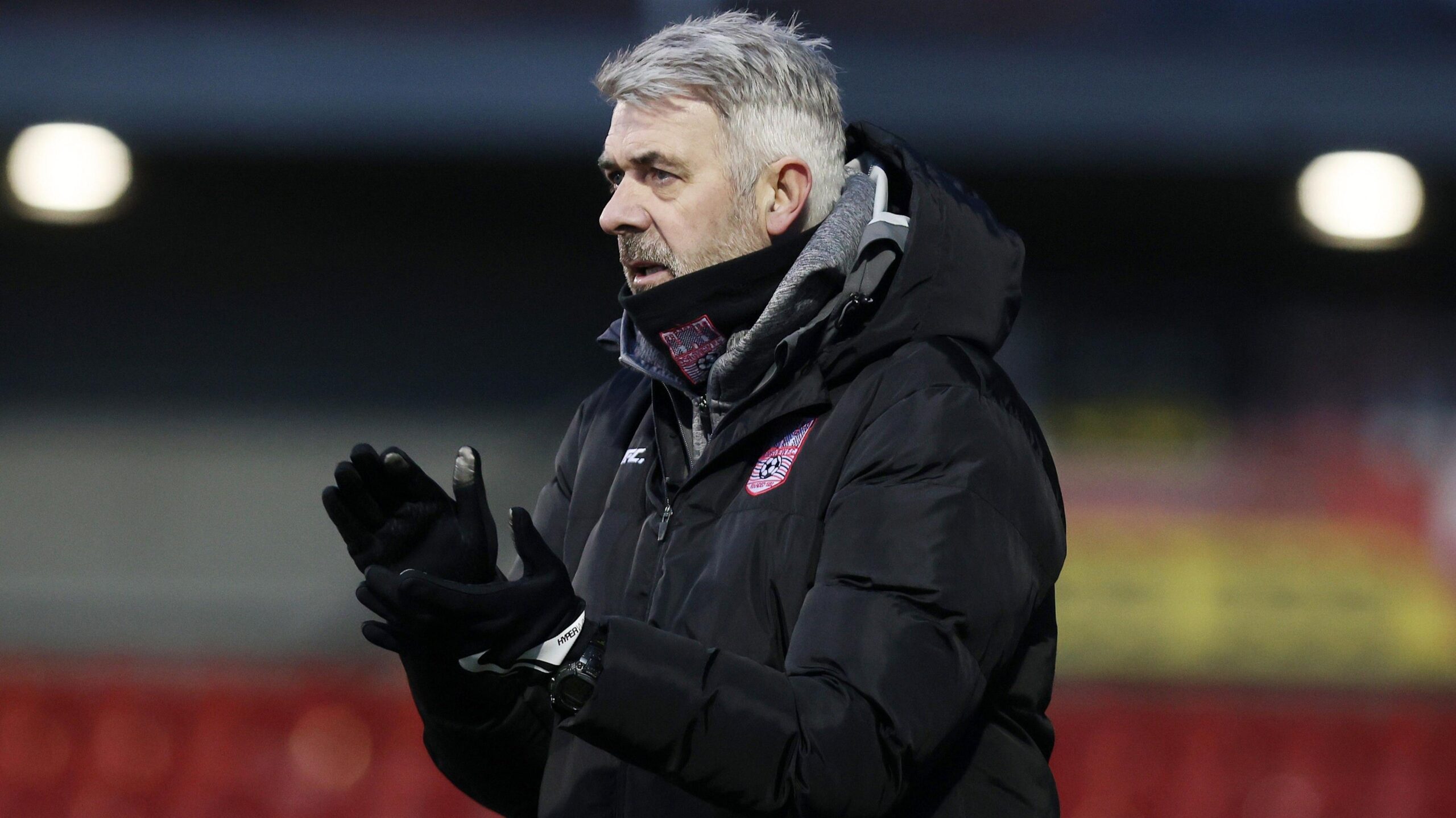 Tommy Canning, in a winter coat and wearing gloves, claps supporters