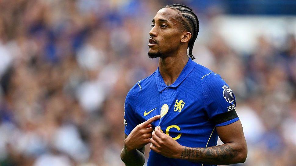 Joao Pedro points at the World Champions badge of Chelsea's shirt