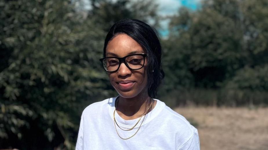 Natasha, wearing a white top and glasses