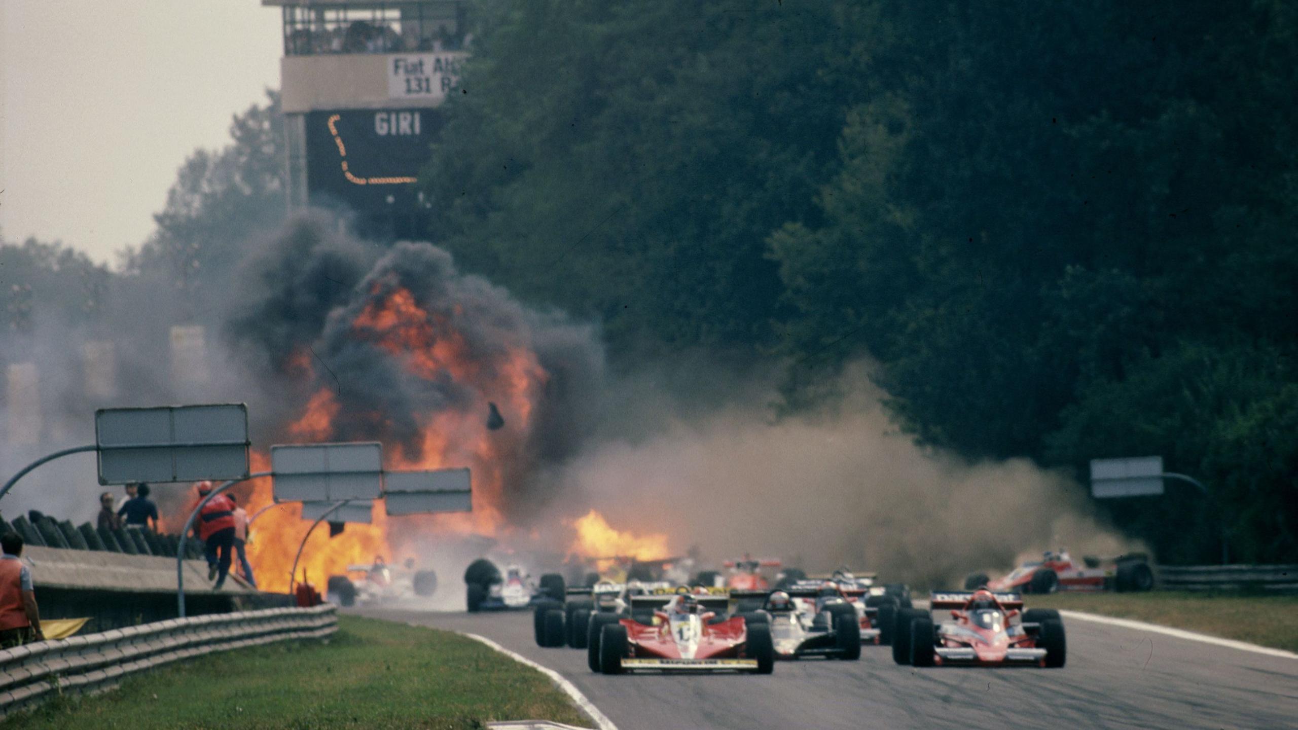 Fire and smoke can be seen in the background with a multi-car accident in process at the start of the 1978 Italian Grand Prix
