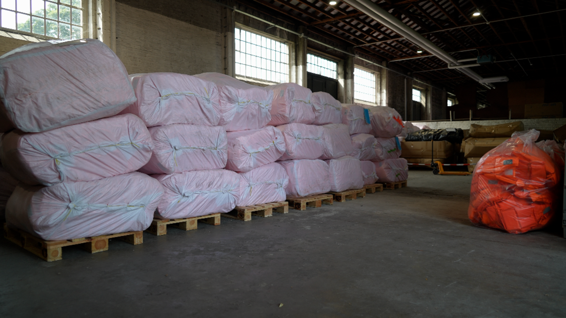A wide shot of plastic bags containing lifejackets in a warehouse