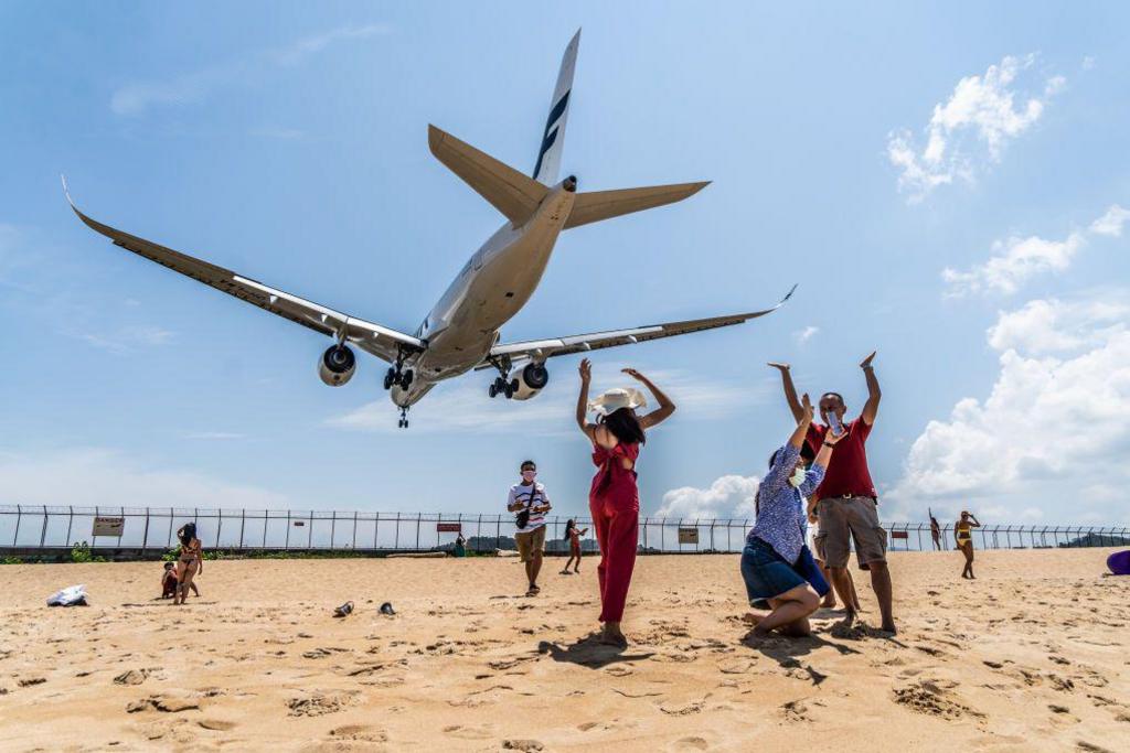 Tourists celebrate at Mai Khao beach as a Finnair jet from Helsinki lands at Phuket International Airport.