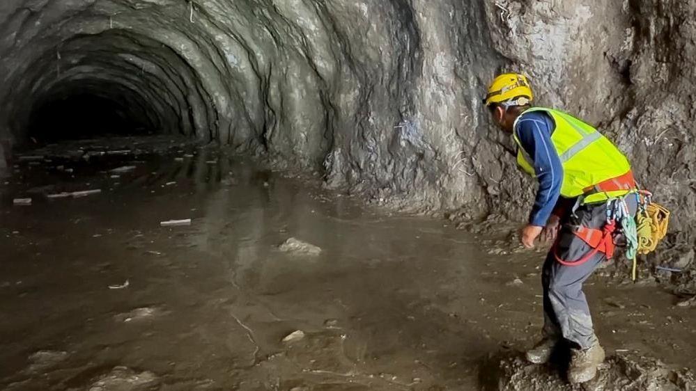 A rescuer works at the entrance of a tunnel at Chilime Hydropower Plant as rescue operations continue for people trapped inside following deadly flash floods and a mudslide, in Rasuwa, Nepal.