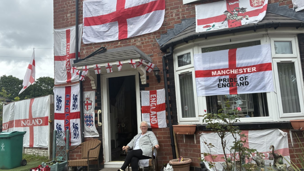 Woman sits in front of house decked with lots of England flags and bunting