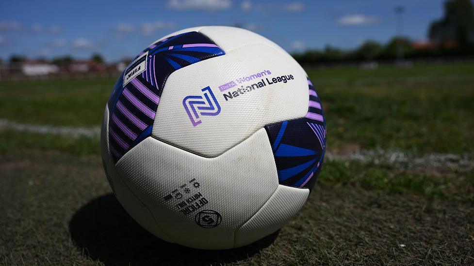 Puple and white football, sitting on grass, with The FA Women's National League written across the middle