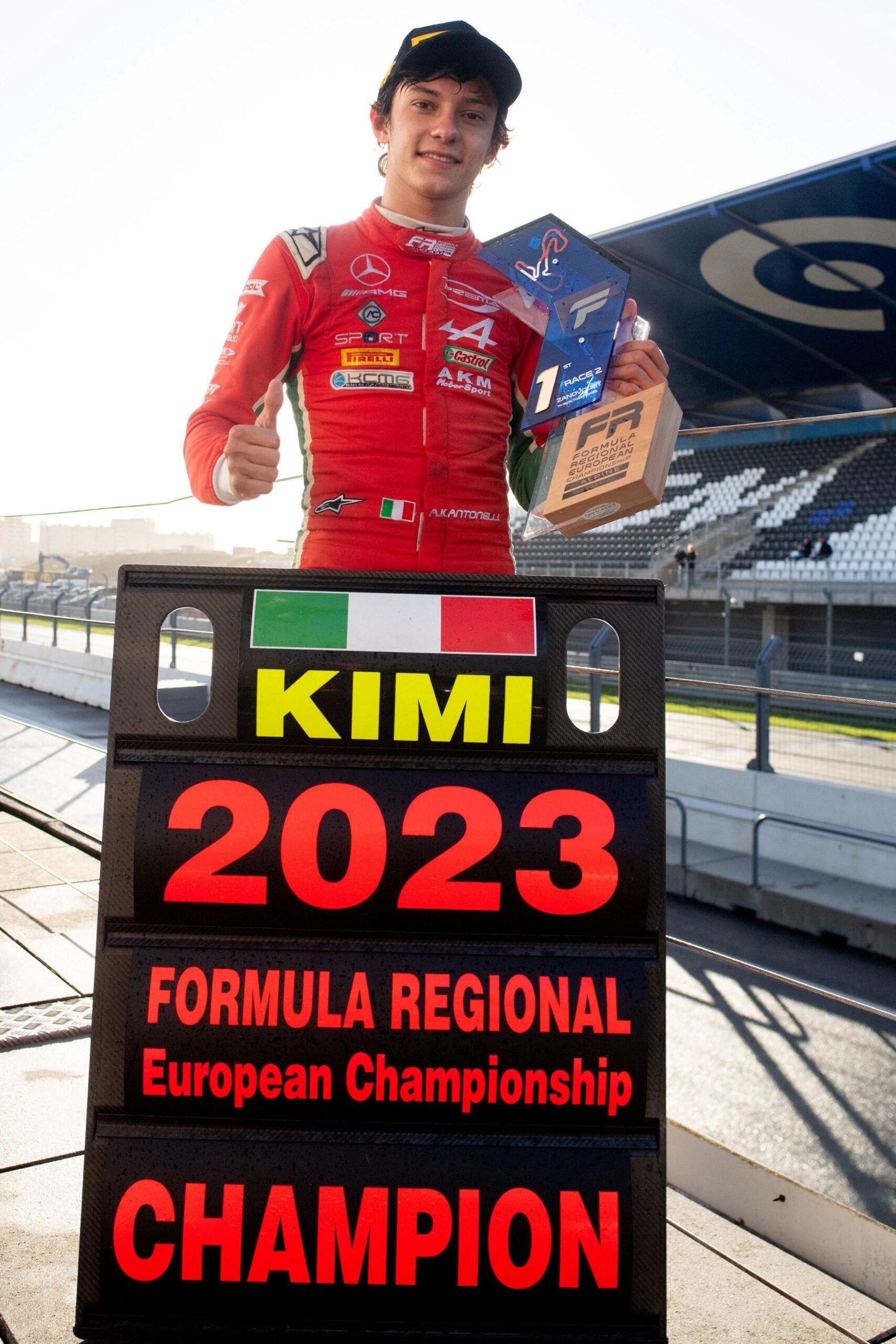 Kimi Antonelli standing behind a pit board sign that refers to him winning the 2023 Formula Regional European Championship