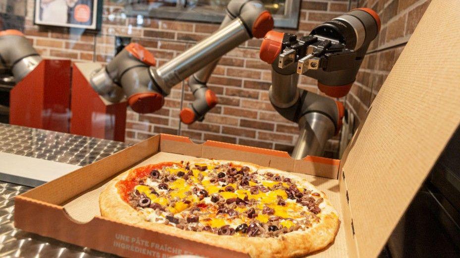 A robot arm hovers over a pizza