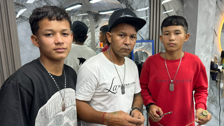 Two teenage boys stand either side of their father.