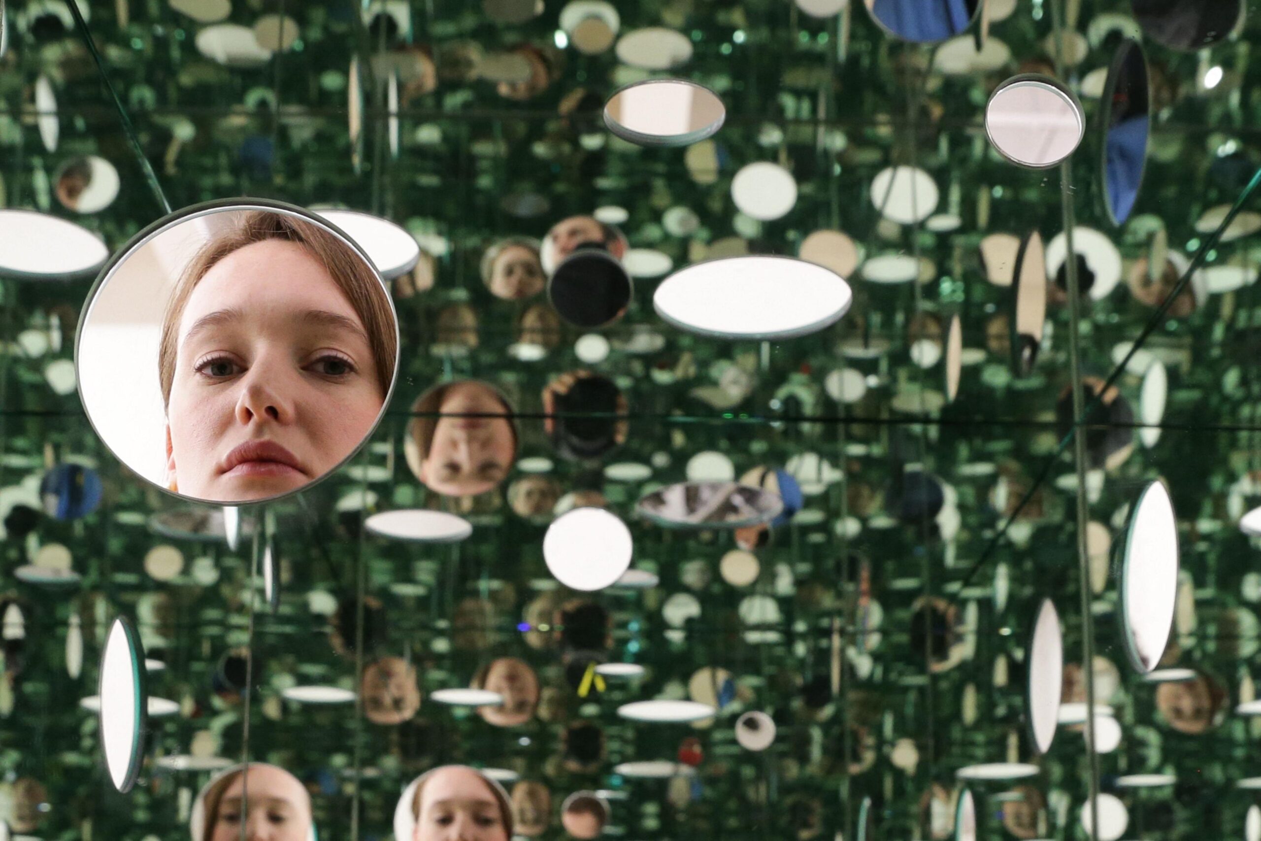 A Kusama installation including numerous round mirrors showing the face of the same young woman, at Tate Modern in London in 2014