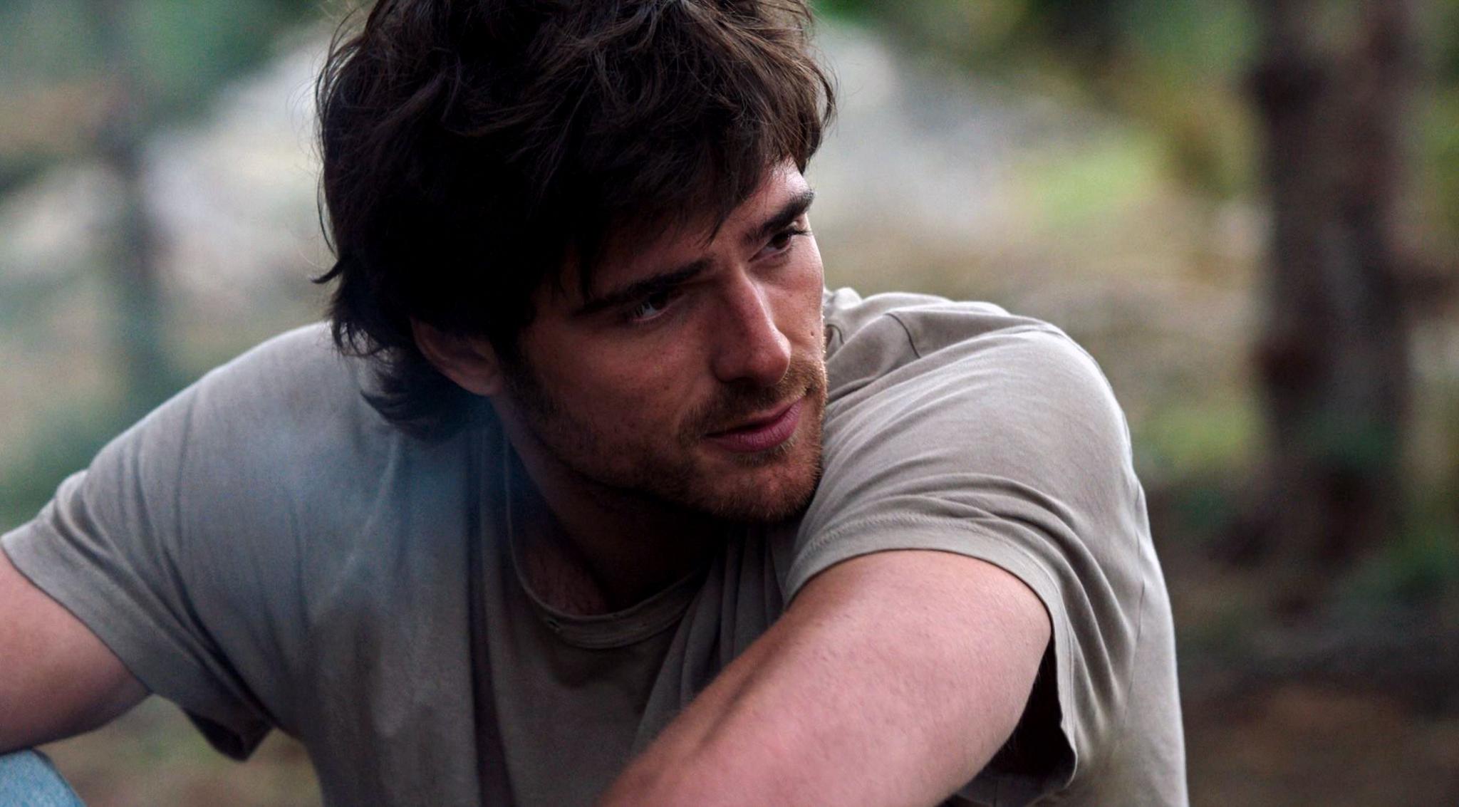 Jacob Elordi appears dishevelled with shaggy hair, a beard and wearing a light green t-shirt.