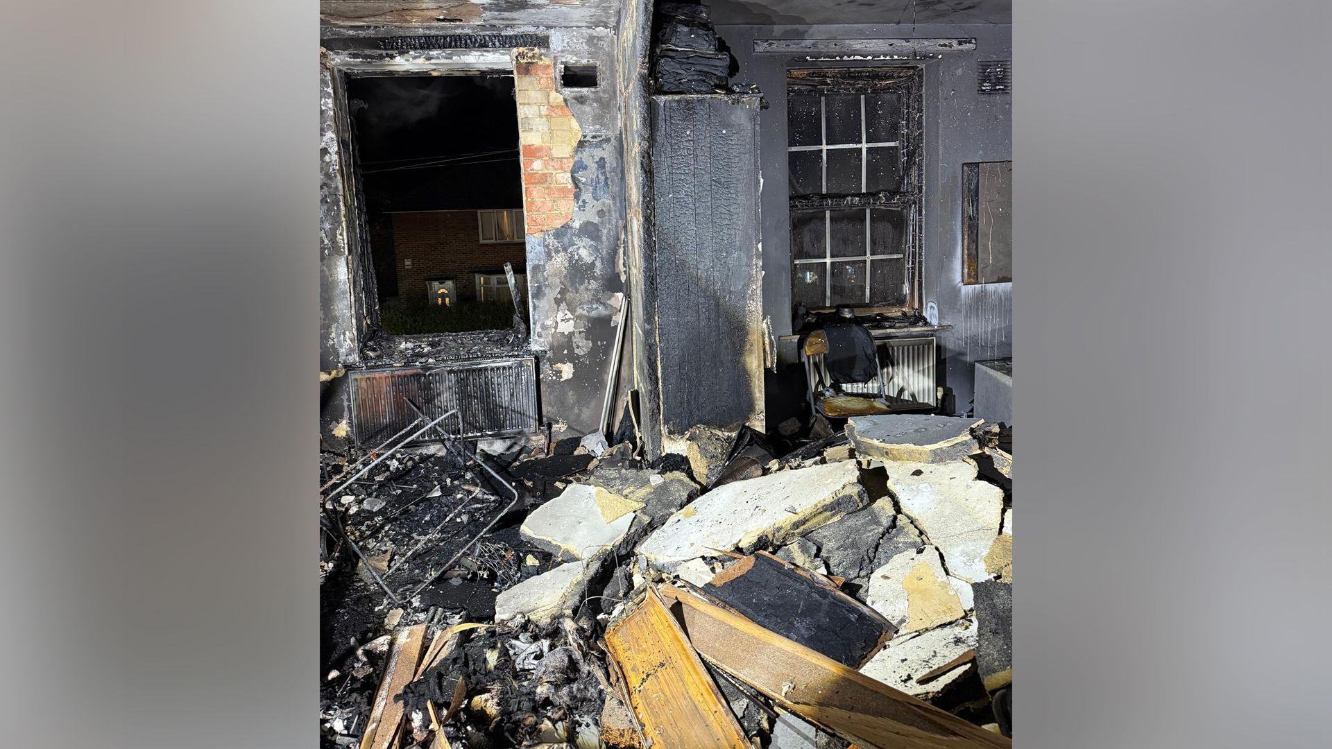 Jahmell Campbell's flat after his e-bike caught fire. The walls have been scorched and huge chunks of the ceiling have been blown apart and can be seen sitting on the floor.