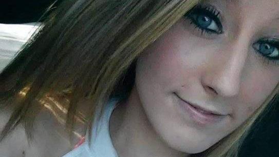 Chelsea Yasser smiles slightly at the camera, her blond hair falling to her chin and shoulders and her eyes made up with heavy mascara and liner