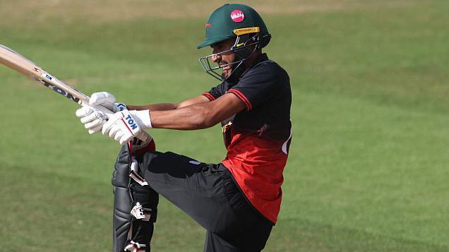 Hamza Shaikh hits a shot for Leicestershire against Kent in the One-Day Cup while wearing a red and black top, black trousers and a green helmet