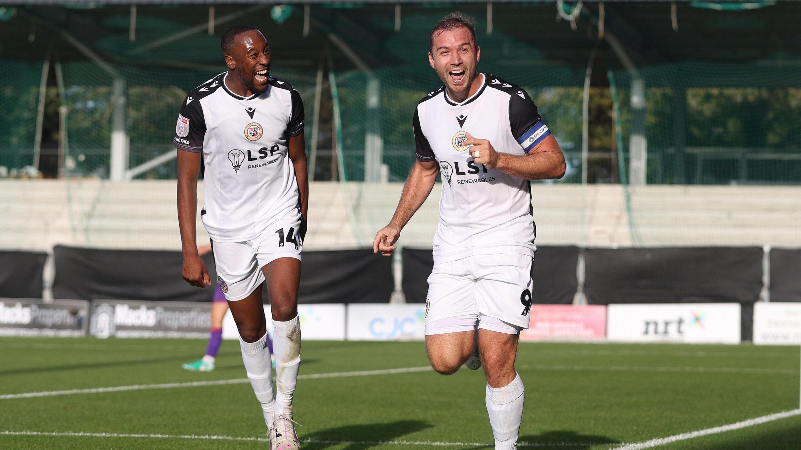 Nicke Kabamba and Michael Cheek celebrate while wearing their white Bromley kits  in their game against Gillingham in September