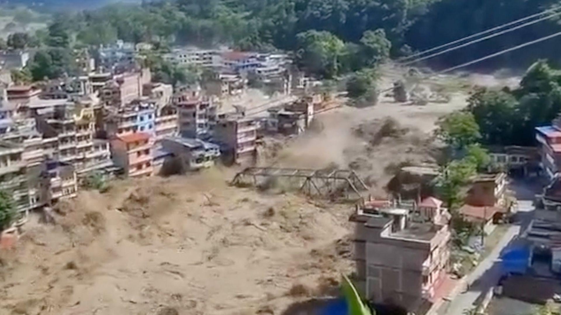 Muddy floodwaters take bridge down in area surrounded by multi-storey buildings