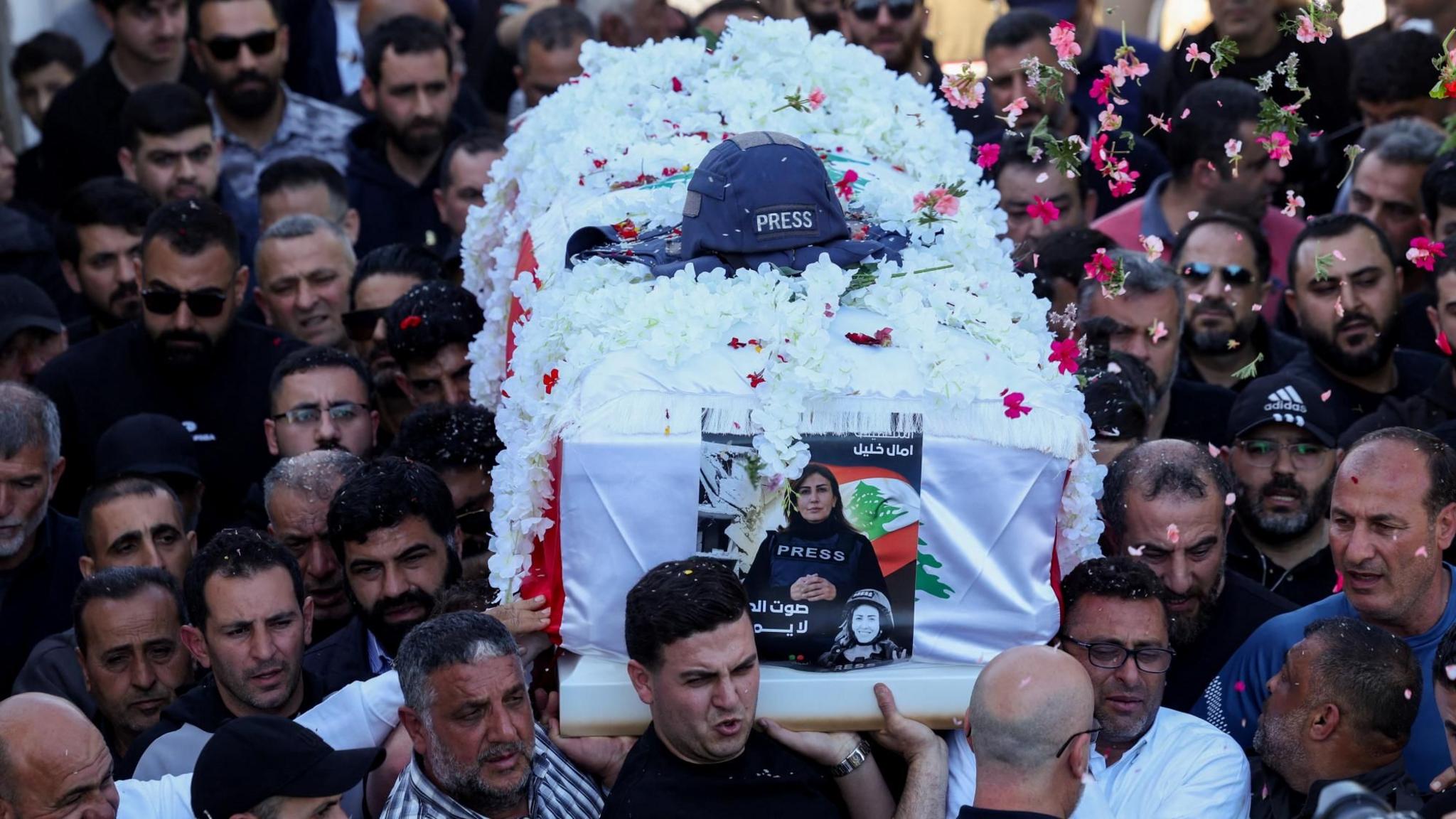 Flowers are thrown over the coffin of journalist Amal Khalil, who was killed in an Israeli strike, as mourners carry it during her funeral in Baisariyeh, Lebanon (23 April 2026)