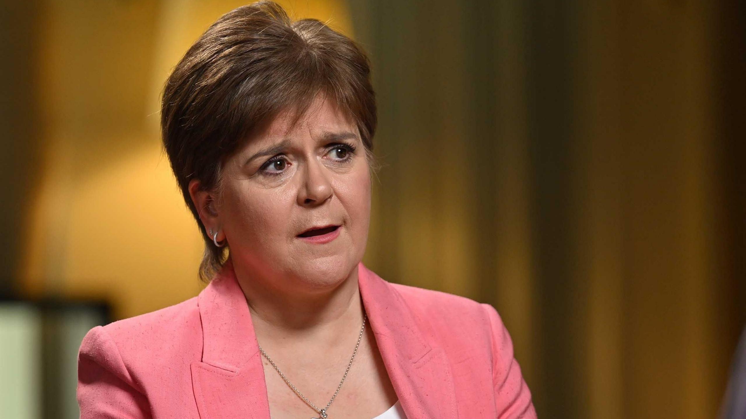 Nicola Sturgeon speaks to Laura Kuenssberg, who is out of shot. Sturgeon is wearing a white top and pink suit