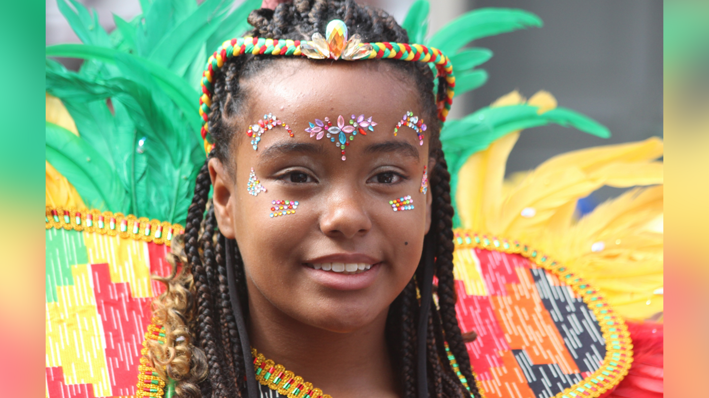 A child with headdress smiles from the parade