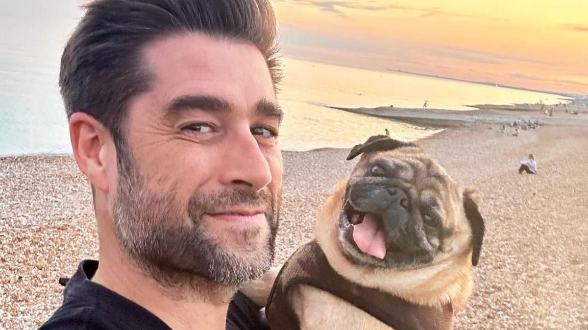 Matt Johnson and his pug Alan Shearer on the beach at sunset