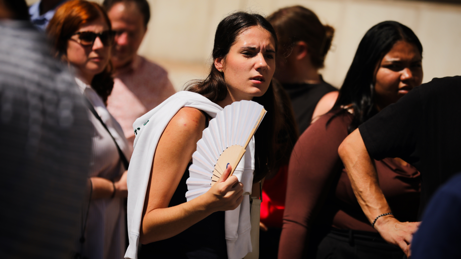 A young woman fans herself in the sunshine on a hot day