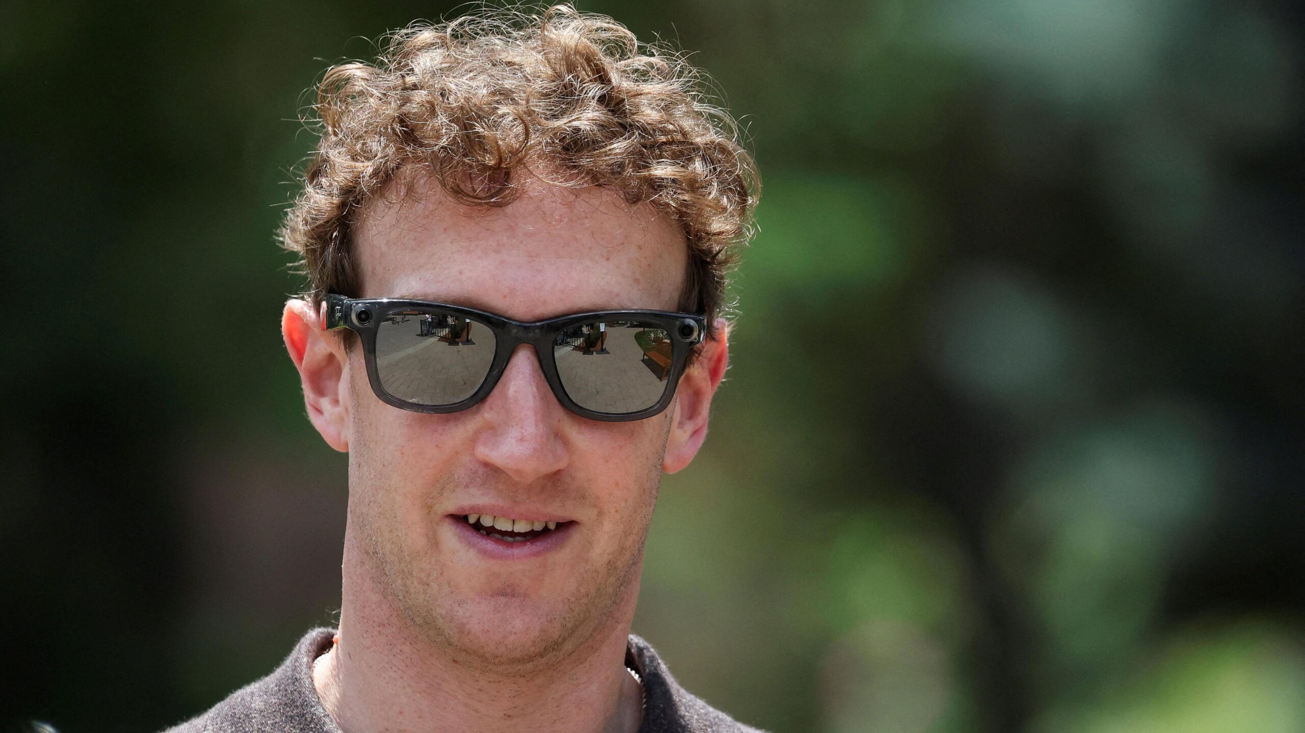 Meta CEO Mark Zuckerberg walking outside wearing a polo-style shirt and a pair of his company's camera-enabled sunglasses.