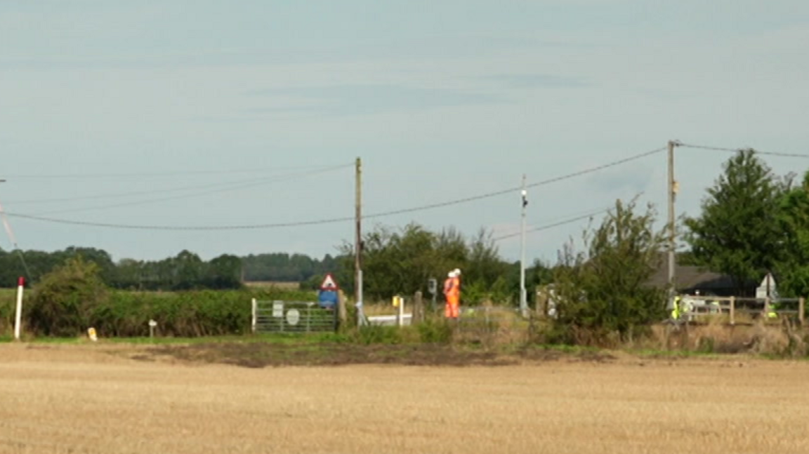 Image shows workmen and police officers at the crossing, which is made up of two gates that, when shut, block access to the line.