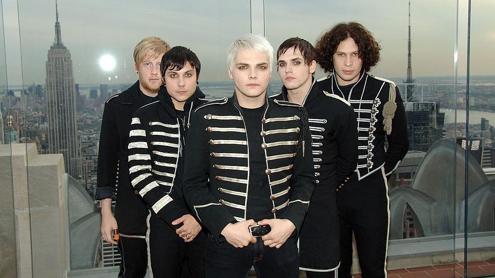 Five men wearing matching vintage military uniform outfits, wearing heavy make up, with several also with facial piercings.