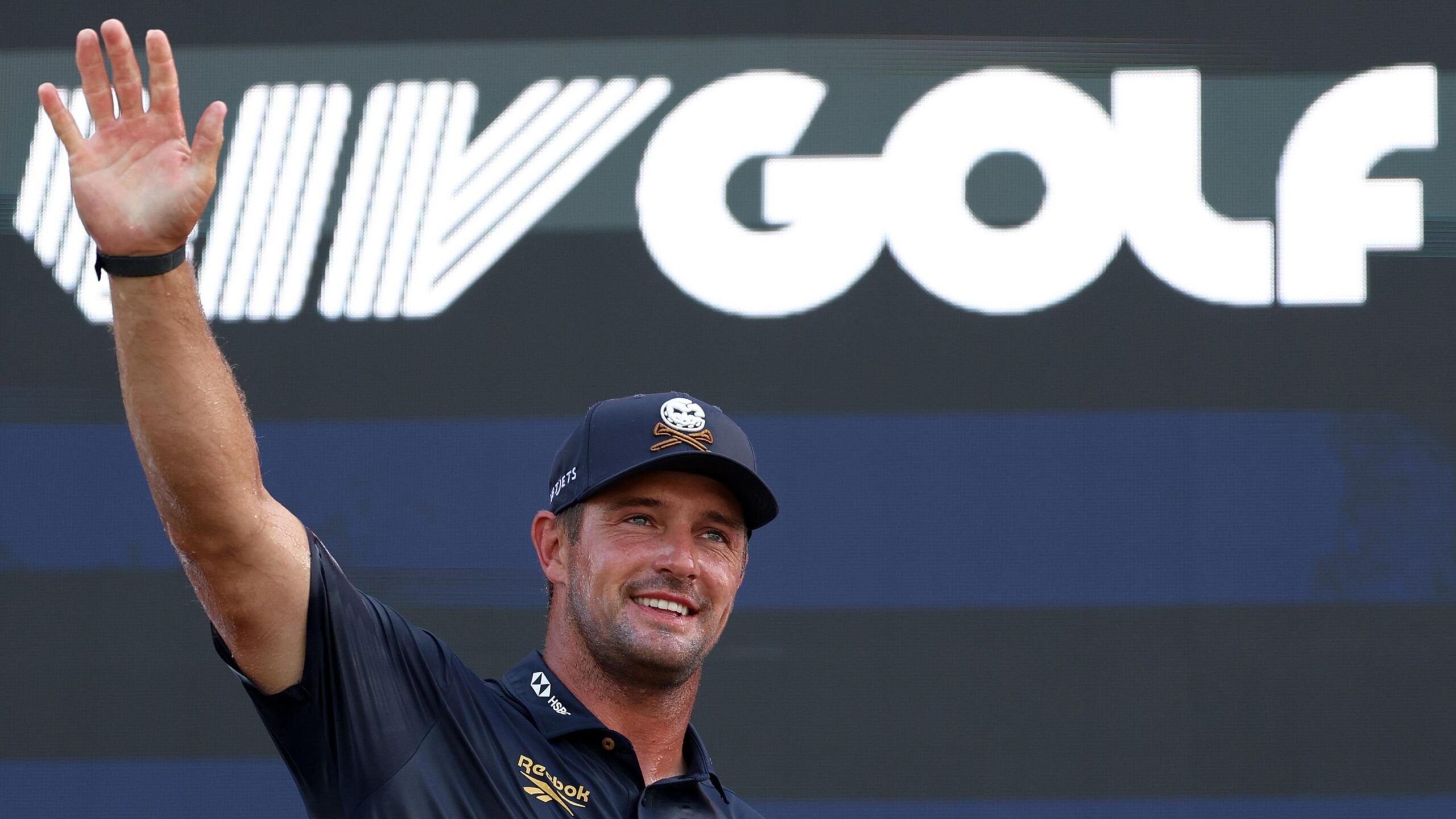 Bryson DeChambeau waves to fans in front of a LIV Golf logo during day four of LIV Golf New York at Trump National Golf Club in August 2026