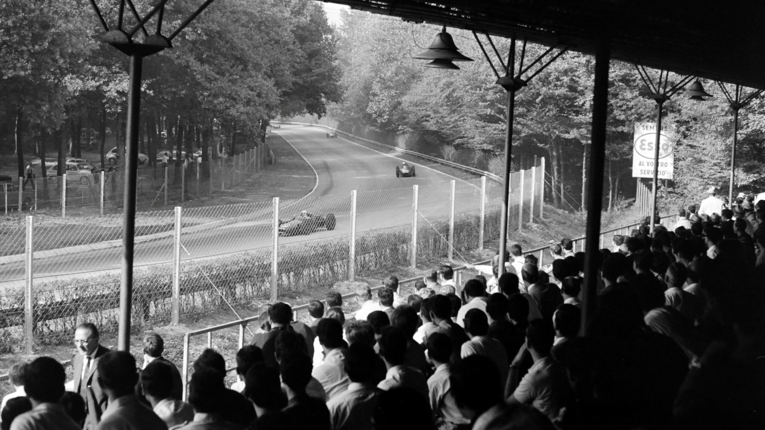 Spectators sat inside a grandstand watching cars go through the Lesmos during the 1962 Italian Grand Prix