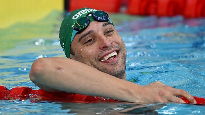 Chad le Clos smiles while holding a lane rope in the swimming pool at Tollcross